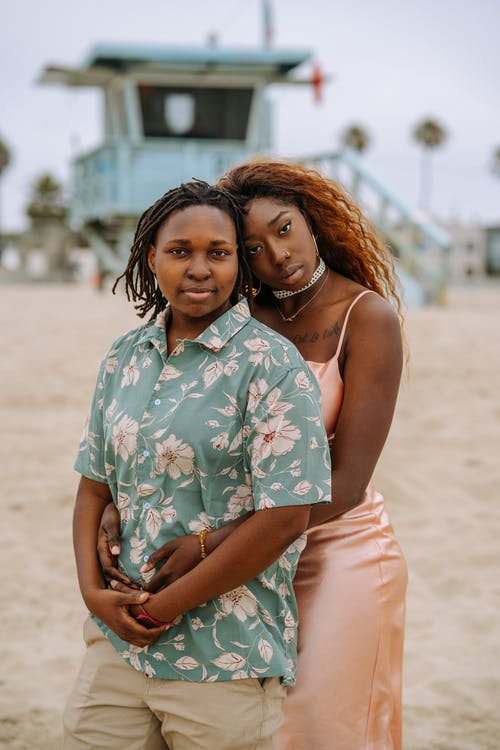 白色和蓝色花无袖连衣裙的女人抱着白色背心的女人 · 免费素材图片