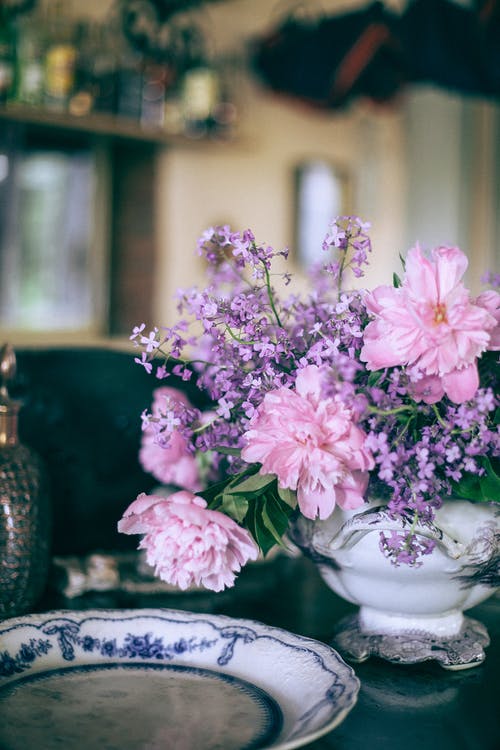 桌上的装饰板附近花瓶里的明亮粉红牡丹 · 免费素材图片