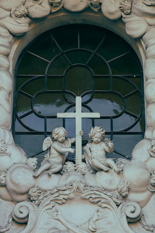 大教堂窗户附近的天使雕塑 · 免费素材图片