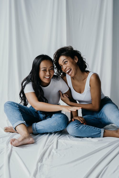 白色背心的女人坐在白色背心的女人旁边的床上 · 免费素材图片