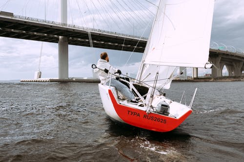 白衬衫和黑色的裤子，坐在红色和白色的船上的人 · 免费素材图片