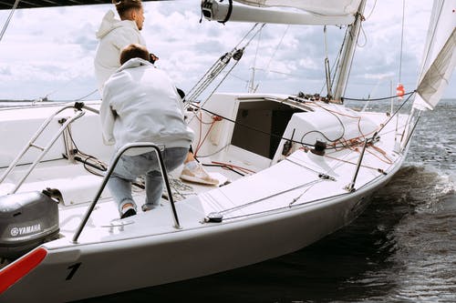 坐在白色和棕色的船上的白色礼服衬衫的男人 · 免费素材图片