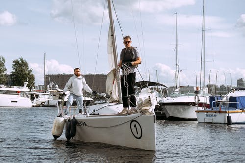 黑色的t恤和黑色的裤子，坐在白色帆船上的男人 · 免费素材图片