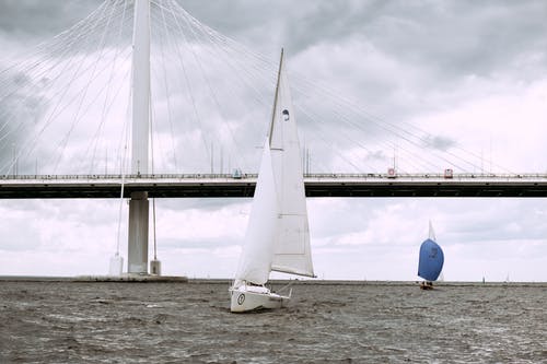 白色帆船在海上附近桥下白云 · 免费素材图片