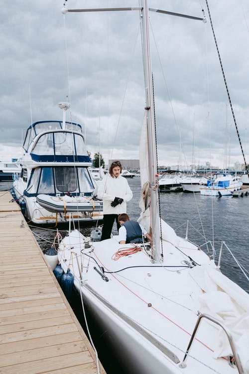 白衬衫和黑色的裤子，坐在白色和蓝色的船上的人 · 免费素材图片