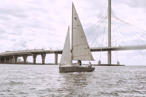 桥附近海上乘船人骑的灰度照片 · 免费素材图片