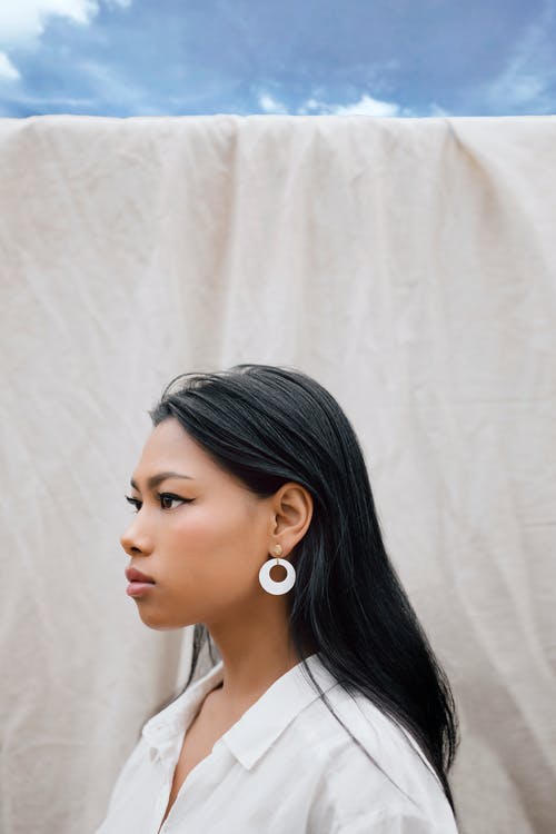 站立在白色板料附近的时髦的年轻种族妇女反对蓝天 · 免费素材图片