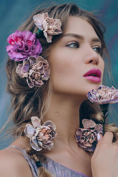 粉红色的唇膏和她的耳朵上的白色和紫色花的女人 · 免费素材图片