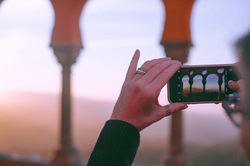 匿名女士拍摄日落时拱形的宫殿 · 免费素材图片