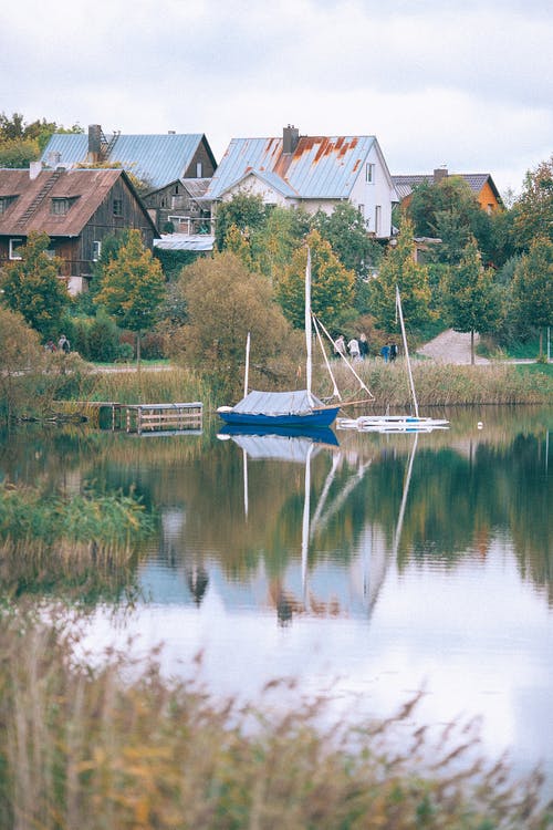蓝船在房屋附近的湖上 · 免费素材图片