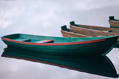 红色和绿色的小船，在蓝蓝的天空下的水 · 免费素材图片