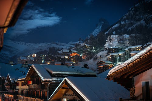 夜间雪山附近的棕色木制房屋 · 免费素材图片