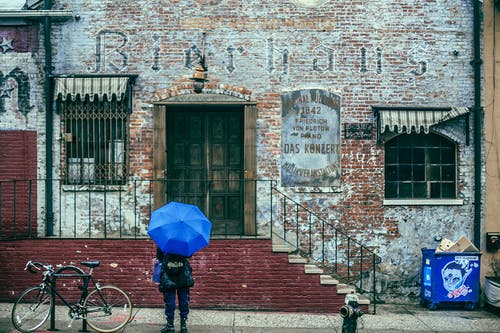 有雨伞的匿名游人在雨天探索城市老区的 · 免费素材图片