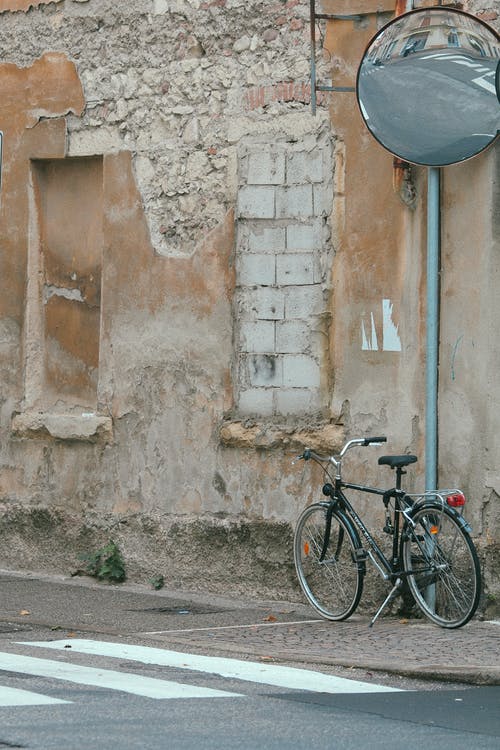 黑色城市自行车停在棕色混凝土墙旁边 · 免费素材图片