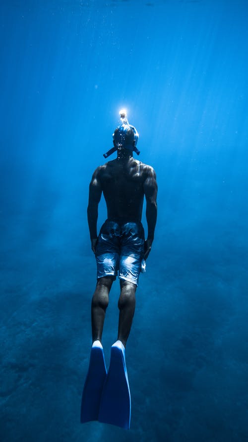 不可识别的人在蓝色的水中潜水 · 免费素材图片