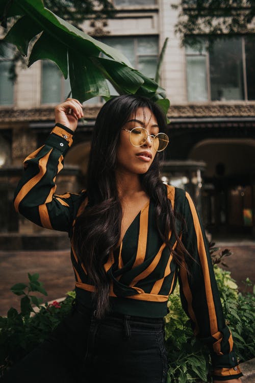 黑色和黄色的长袖连衣裙，拿着绿叶的女人 · 免费素材图片