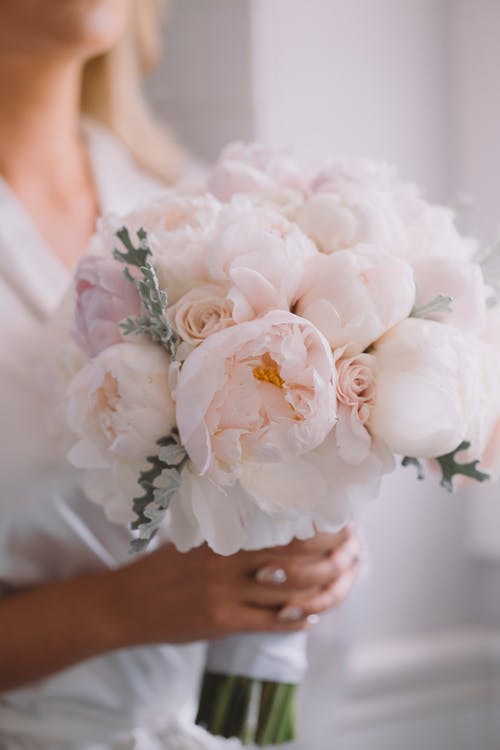 拿着白花花束的白色婚礼礼服的妇女 · 免费素材图片