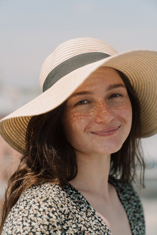 微笑的女士戴着棕色和白色的太阳帽 · 免费素材图片