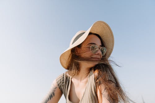白色和黑色条纹背心戴棕色太阳帽的女人 · 免费素材图片