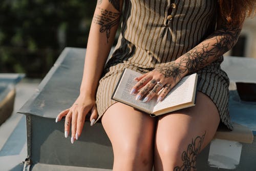 棕色和黑色条纹裙子阅读书中的女人 · 免费素材图片