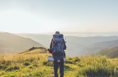 站在小山对薄雾笼罩的风景秀丽的不可识别的男性旅行者 · 免费素材图片