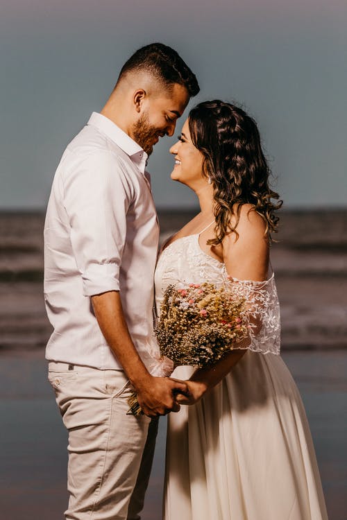 浪漫的年轻种族新婚夫妇手牵着手在沙滩上 · 免费素材图片