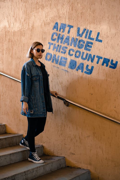 走下楼梯与标题墙附近的时尚女人 · 免费素材图片