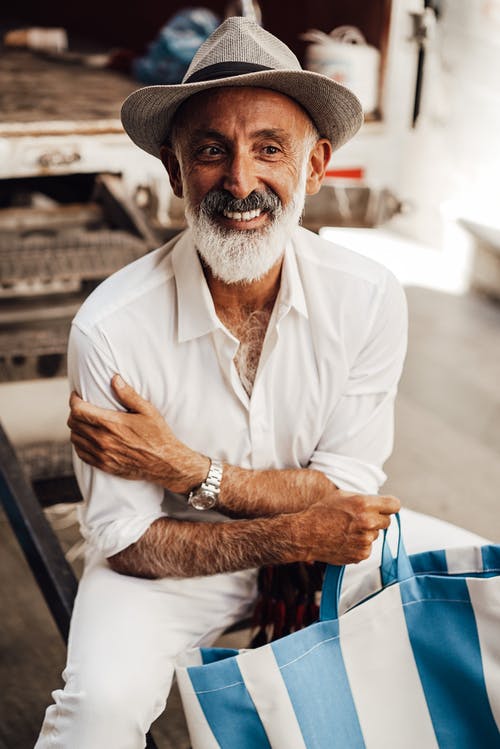 有大手提袋的微笑的老人坐街道 · 免费素材图片