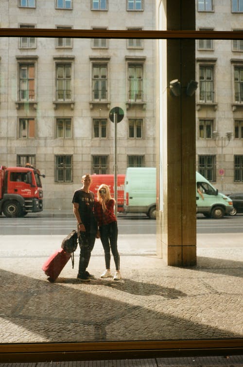 几个认不出来的旅行者带着手提箱在城市路面上 · 免费素材图片