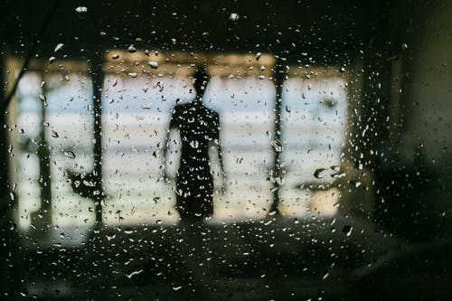 雨滴窗口后面的匿名男子 · 免费素材图片