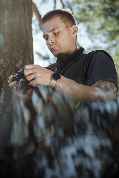 拿着黑色单反相机的黑色圆领t恤的男人 · 免费素材图片