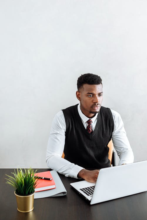 坐在桌前的黑色背心和白色礼服衬衫的男人 · 免费素材图片