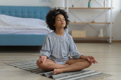 在房间的地毯上冥想的黑人孩子 · 免费素材图片