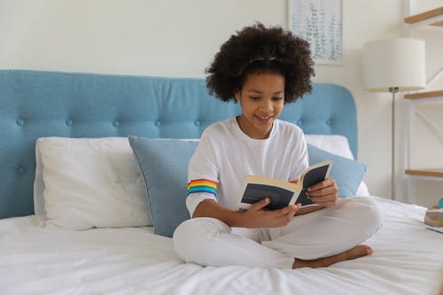 在床上的黑人女孩阅读书 · 免费素材图片