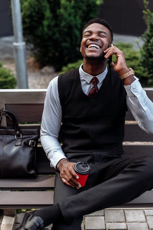 黑色背心和白色礼服衬衫坐在长凳上的男人 · 免费素材图片