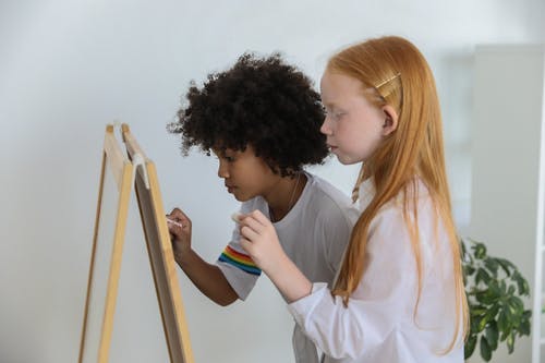 冷静在画架黑板上绘画的多种族女孩 · 免费素材图片