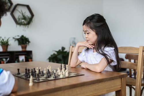 下棋用手在下巴的亚洲女孩 · 免费素材图片