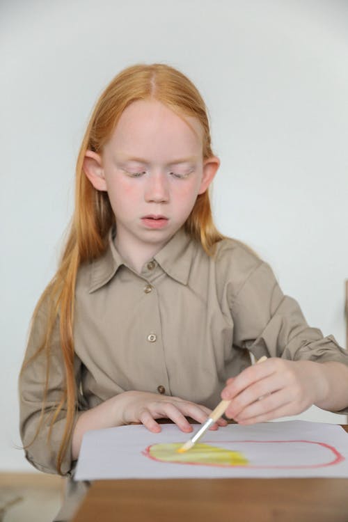 严重的红发孩子在纸上画用画笔和水彩画 · 免费素材图片