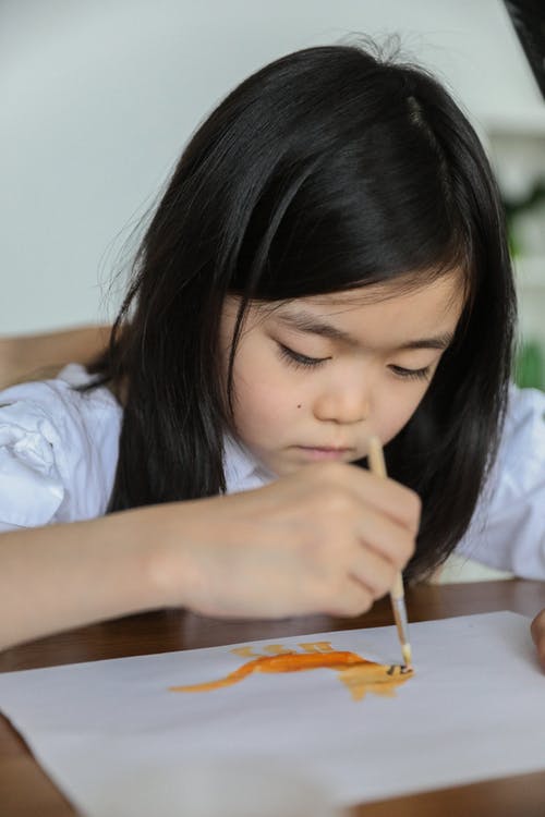 严重的亚洲孩子绘画与水彩画在艺术工作室 · 免费素材图片