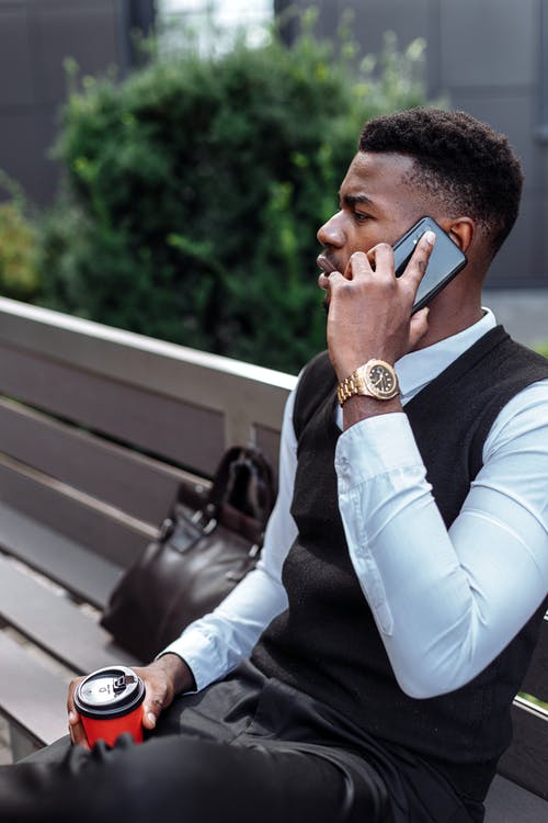 黑色背心和白色礼服衬衫坐在长凳上的男人 · 免费素材图片