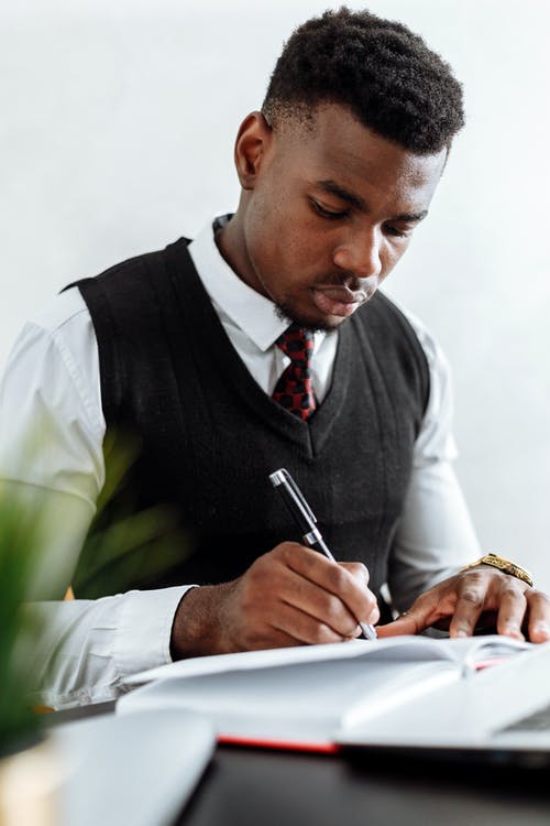 黑背心手握一支笔的人 · 免费素材图片