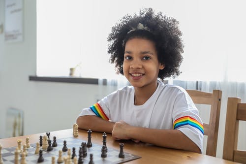 在房间的桌子下棋的黑人女孩 · 免费素材图片