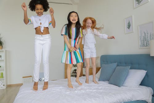 快乐嬉戏多样的女孩在床上跳 · 免费素材图片