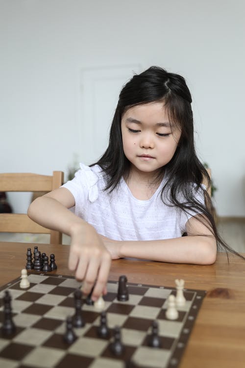 下棋的严肃的亚裔女孩在桌上 · 免费素材图片