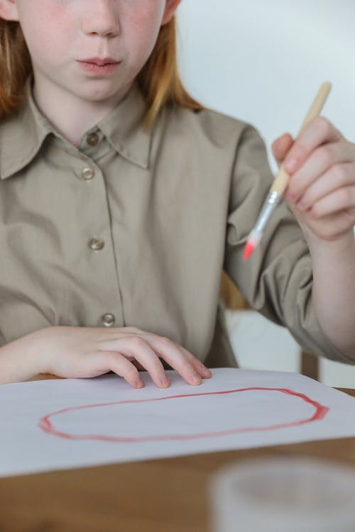 严重的孩子在纸上用水彩画画椭圆形 · 免费素材图片