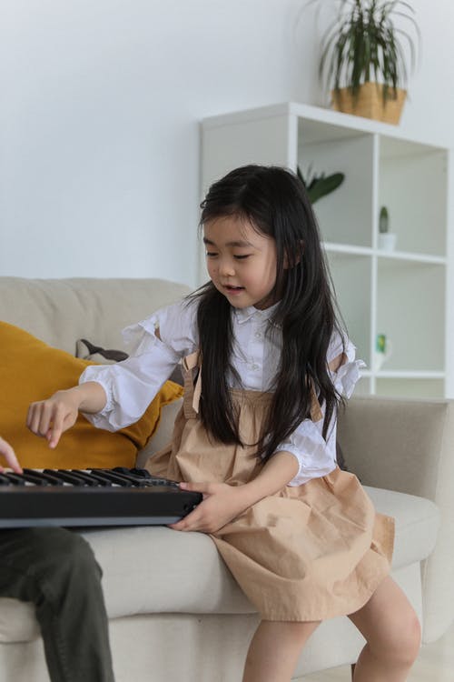 可爱的亚洲小女孩在玩合成器 · 免费素材图片