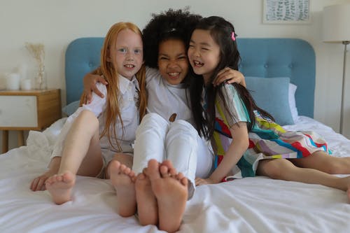 多种族的快乐赤脚女孩在床上做鬼脸 · 免费素材图片
