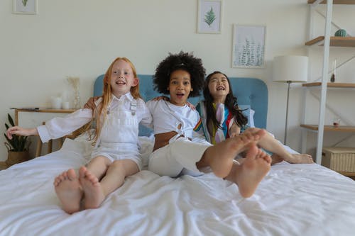 可爱有趣开朗多种族的女孩在床上休息和笑 · 免费素材图片