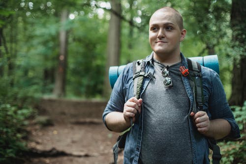 积极丰满的男性徒步旅行者背包在树林里 · 免费素材图片