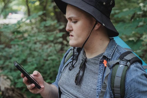 集中年轻男性背包客检查自然界中智能手机的位置 · 免费素材图片